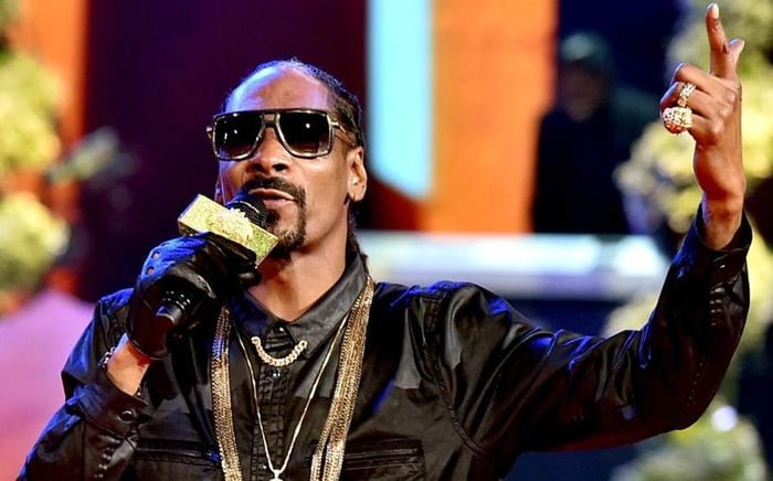 Snoop Dogg de roupa preta e oculos escuros segura microfone - metrópoles