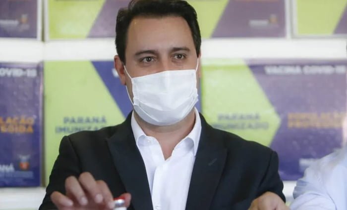 O governador do Paraná, Ratinho Junior, em evento. Ele discursa usando uma máscara facial branca, vestindo um terno preto e uma camisa social branca - Metrópoles