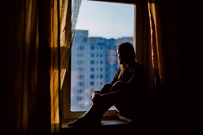 imagem colorida de mulher sentada na janela com depressão - Metrópoles