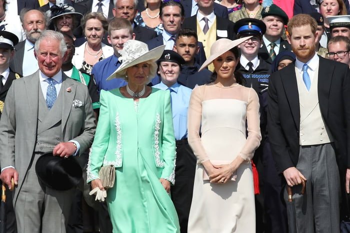 Foto colorida de grupo de pessoas enfileiradas. Os homens estão com terno e as mulheres, com vestidos e chapéus monocromáticos - Metrópoles