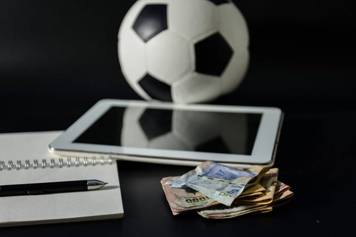 Imagem colorida de dinheiro, tablet, bola de futebol e vício
