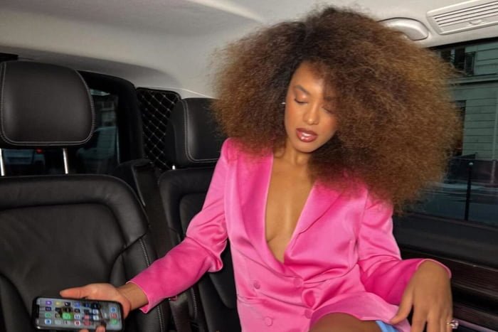 Na imagem com cor, uma mulher negra em um carro usando um blazer rosa - Metrópoles