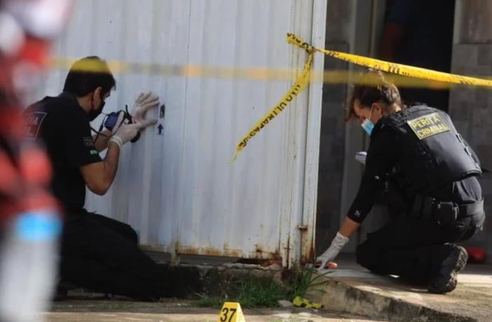 Dois homens com roupas pretas agachados fazendo a perícia de uma cena de crime - Metrópoles
