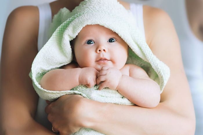 bebe segurando pela mãe enroladinho em-uma toalha - Metrópoles
