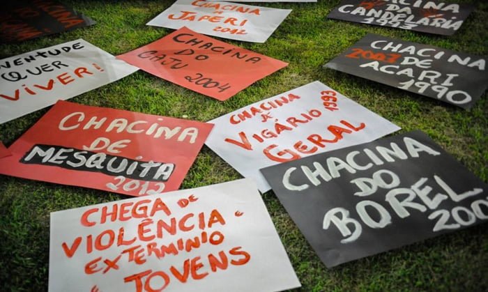 Imagem colorida de cartazes que lebram os 30 anos da Chacina da Candelária, no Rio