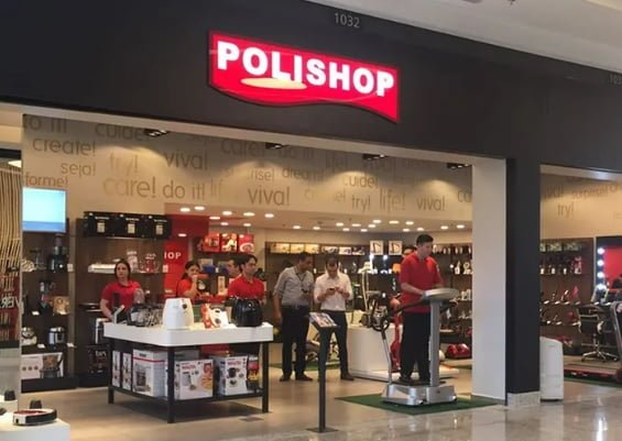 Imagem da entrada de loja da Polishop em um shopping center. Na parte de cima, logotipo da empresa com letras na cor branca e fundo vermelho. Abaixo, ao centro, funcionários trabalhando - Metrópoles