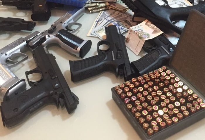 Caixa de municão, armas e notas dinheiros sobre uma mesa - Metrópoles