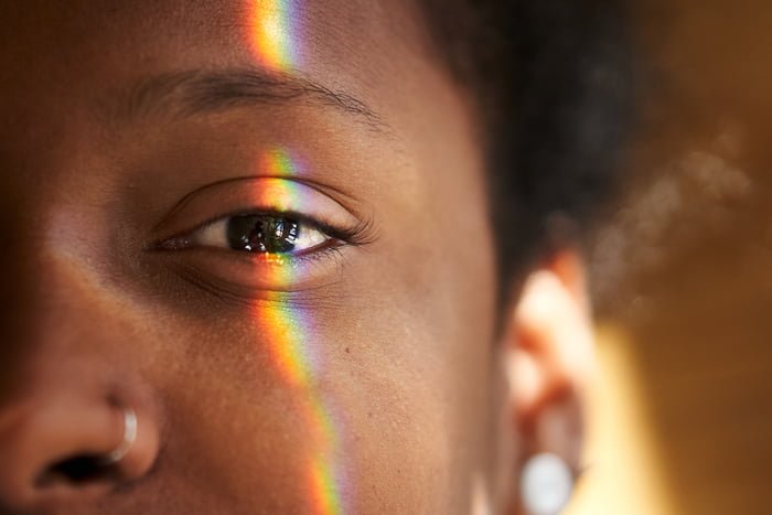 Foto colorida. Imagem foca no olho da mulher negra e um fecho de luz do sol está focado