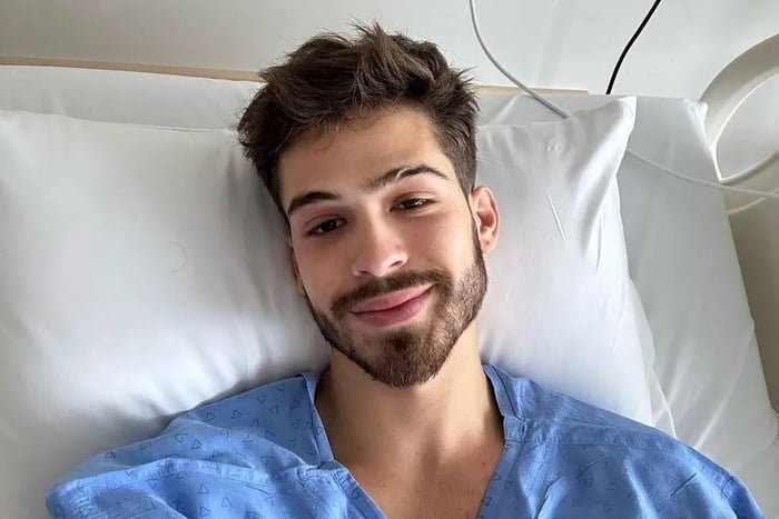 Foto colorida de João Guilherme de barba e sorrindo em maca de hospital - Metrópoles