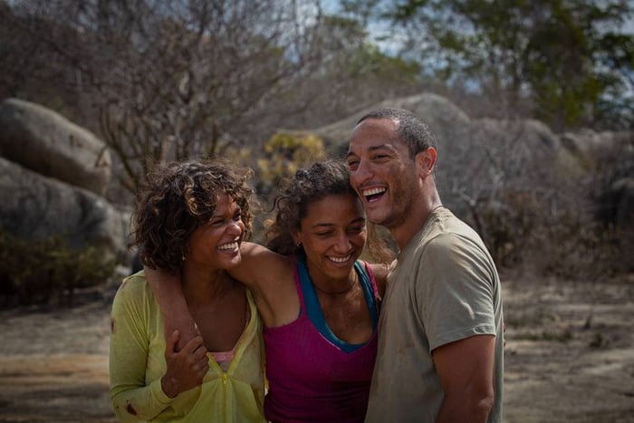 Foto colorida do elenco da série Cangaço Novo, com duas mulheres e um homem abraçados no sertão - Metrópoles