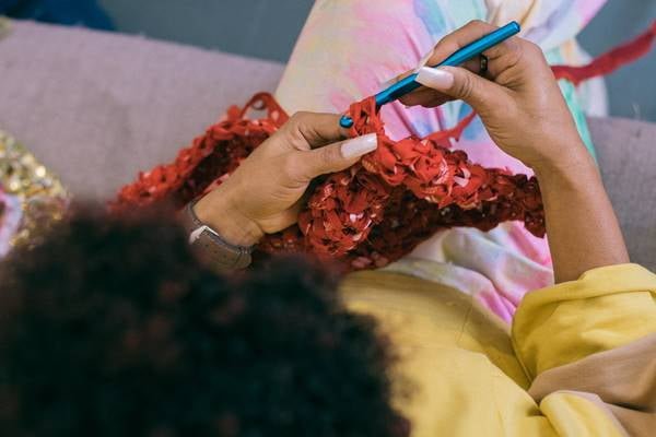 Na imagem de cima, mulher faz crochê vermelho - Metrópoles