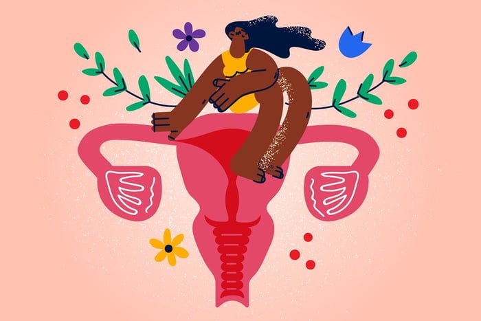 Ilustração colorida mostra mulher negra sentada em cima de um útero, com flores atrás - Metrópoles