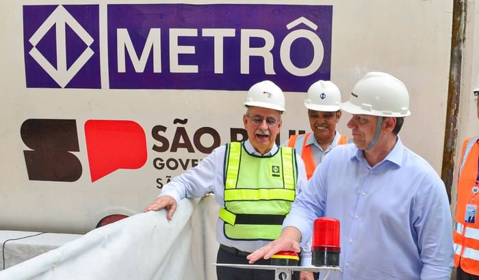 Foto colorida do governador Tarcísio de Freitas, de capacete e camisa azul, apertando botão em canteiro de obra do Metrô - Metrópoles