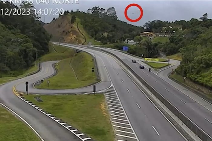 Frame colorido de imagem de câmera de segurança. Trata-se de uma estrada, com um ponto vermelho assinalado atrás - Metrópoles