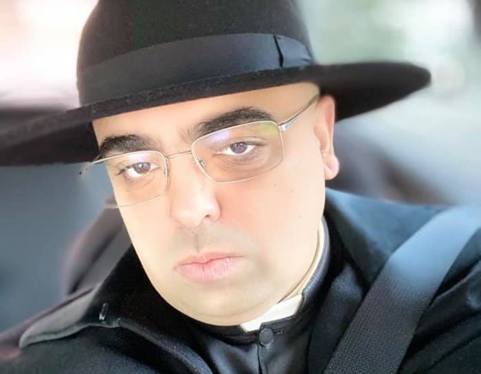 Foto colorida do padre José Eduardo de Oliveira e Silva, de óculos e chápeu preto
