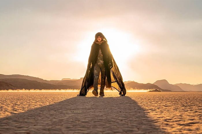 Homem com capa andando pelo meio do deserto no filme Duna 2