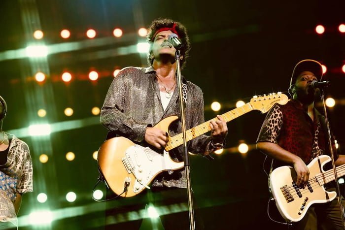 Foto colorida de Bruno Mars com uma guitarra em frente ao microfone em show na Filipinas, Ásia - Metrópoles