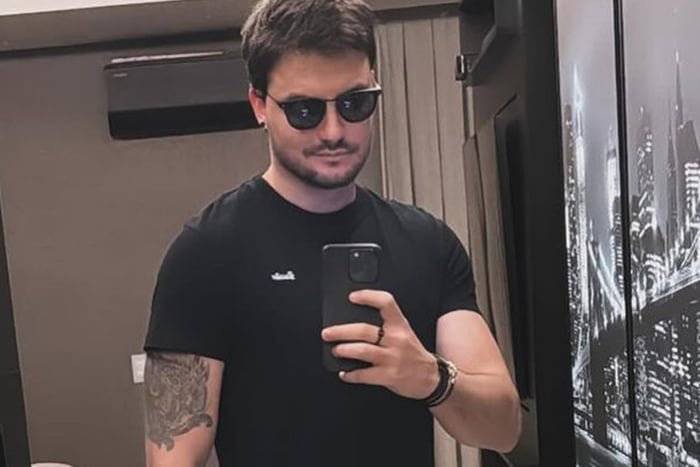Felipe Neto posa de camiseta preta, óculos escuros e celular na mão - Metrópoles