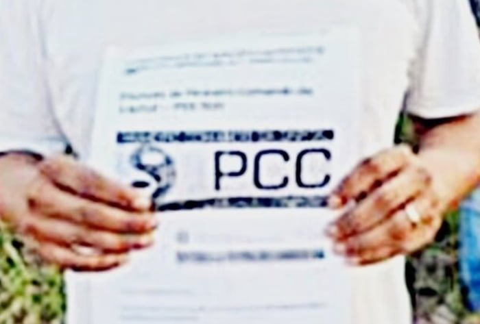 Homem segura papel com a sigla PCC