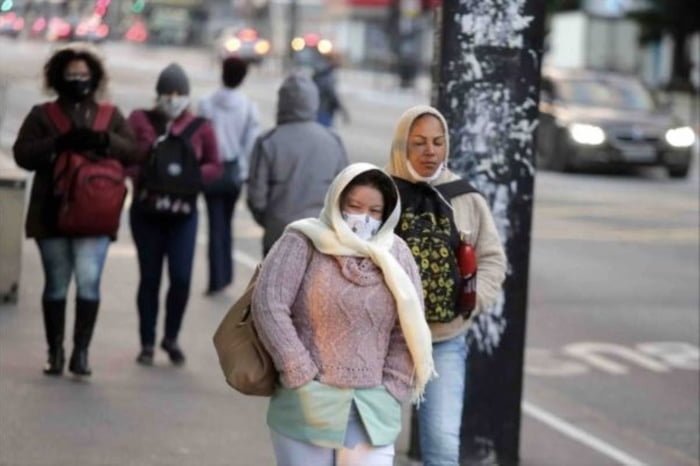 Mulher caminha em rua de São Paulo vestindo blusa, touca, máscara e cachecol. Ela tem as mãos no bolso La Niña - Metrópoles