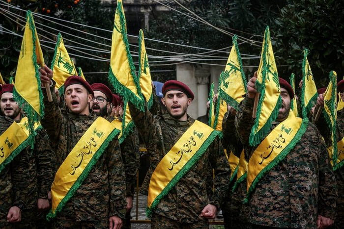 Imagem colorida mostra membros do Hezbollah com os braços levantados - Metrópoles