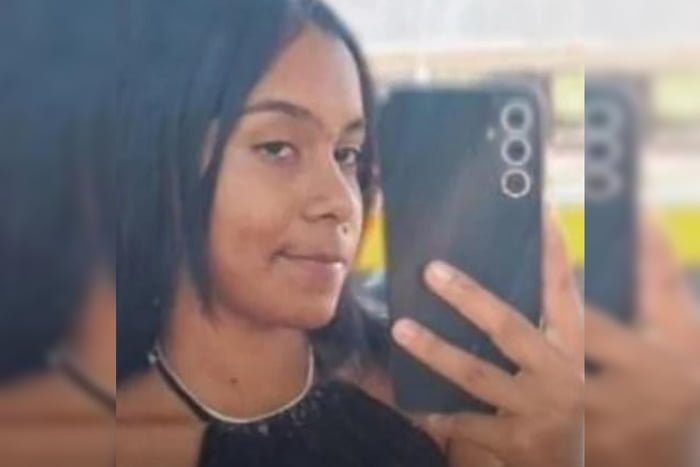 Imagem colorida de jovem com cabelo preto segurando celular
