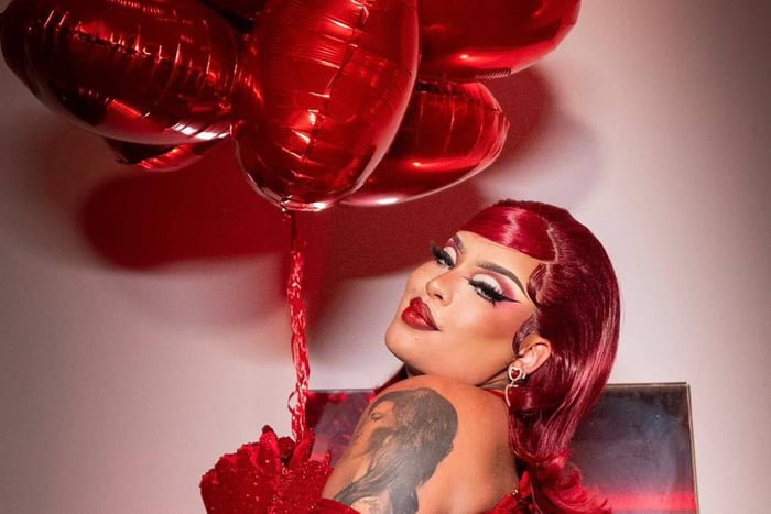Gloria Groove com cabelos vermelhos segurando balões de coração - Metrópoles