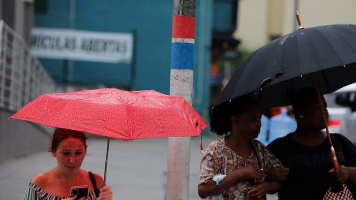 Imagem colorida de pessoas durante chuva em Santa Catarina - Metrópoles