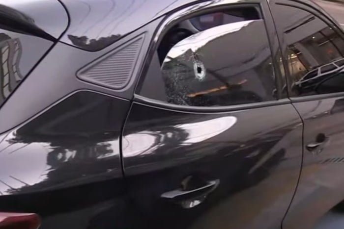Imagem colorida de carro preto com marca de tiro no vidro. Policial estava dentro do carro e reagiu a assalto - Metrópoles