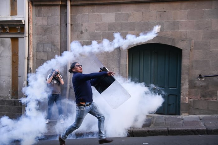 Manifestante arremessa gás lacrimogêneo em frente ao palácio presidencial na Plaza Murillo - metrópoles