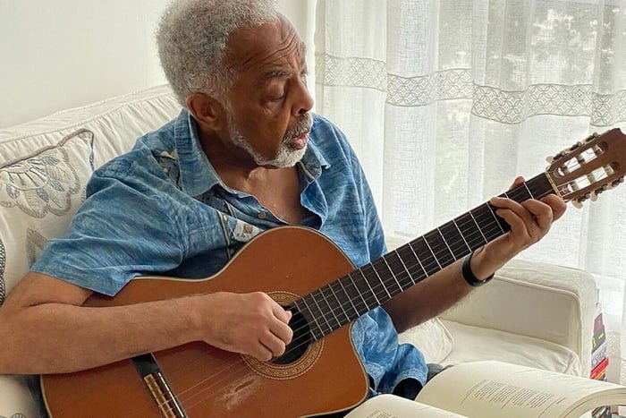 Gilberto Gil posa com um violão e um livro - Metrópoles