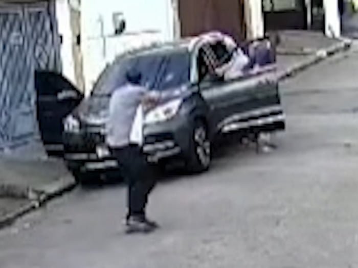 Imagem mostra homem armado em frente a um carro - Metrópoles