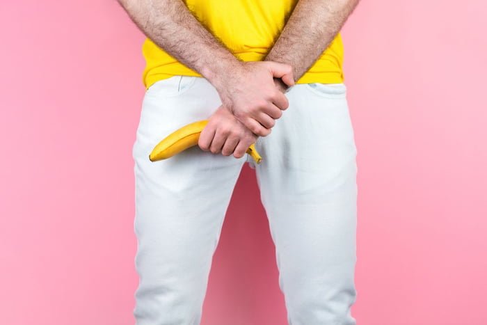 homem de blusa amarela segurando uma banana