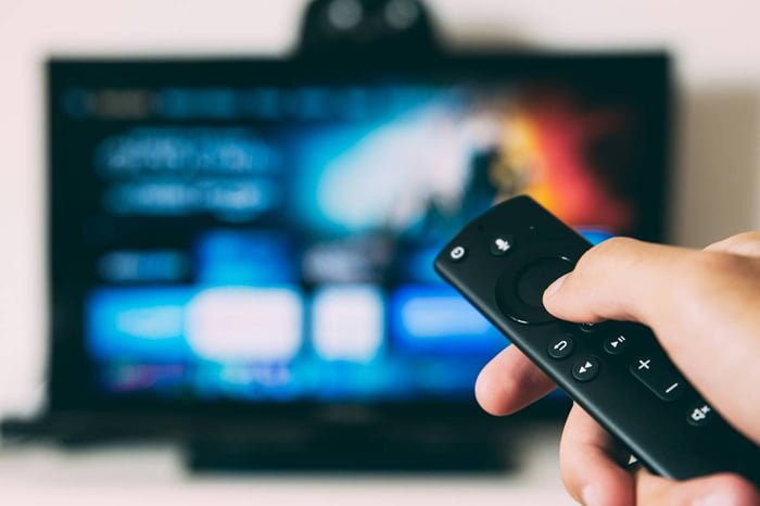 Homem apontando controle remoto para a TV com uma logo do prime video - Metrópoles