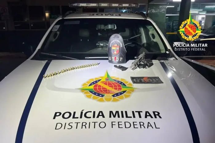 Foto colorida de arma e munições em cima de capo de viatura da policia militar