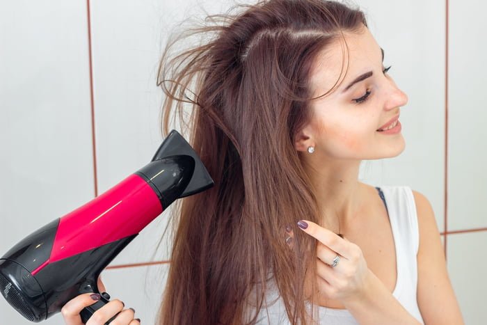 Foto de mulher passando o secador no cabelo - Metrópoles